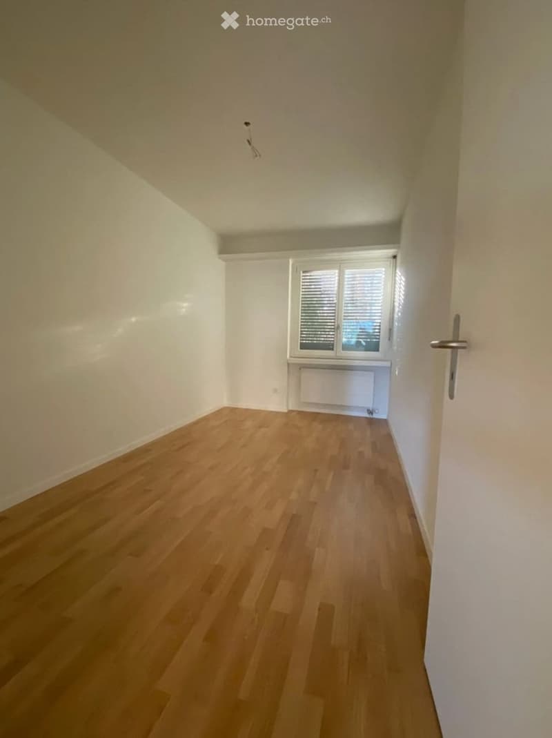 Empty room with light wooden flooring, white walls, and a window with blinds. No furniture or equipment present.