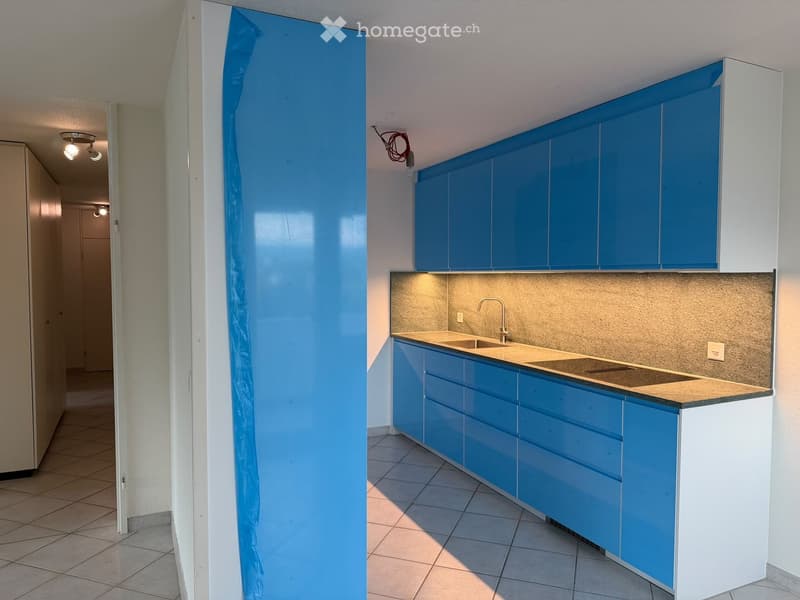 Modern kitchen with blue cabinets, white countertops, and a sink. The space is clean and well-lit with recessed lighting.