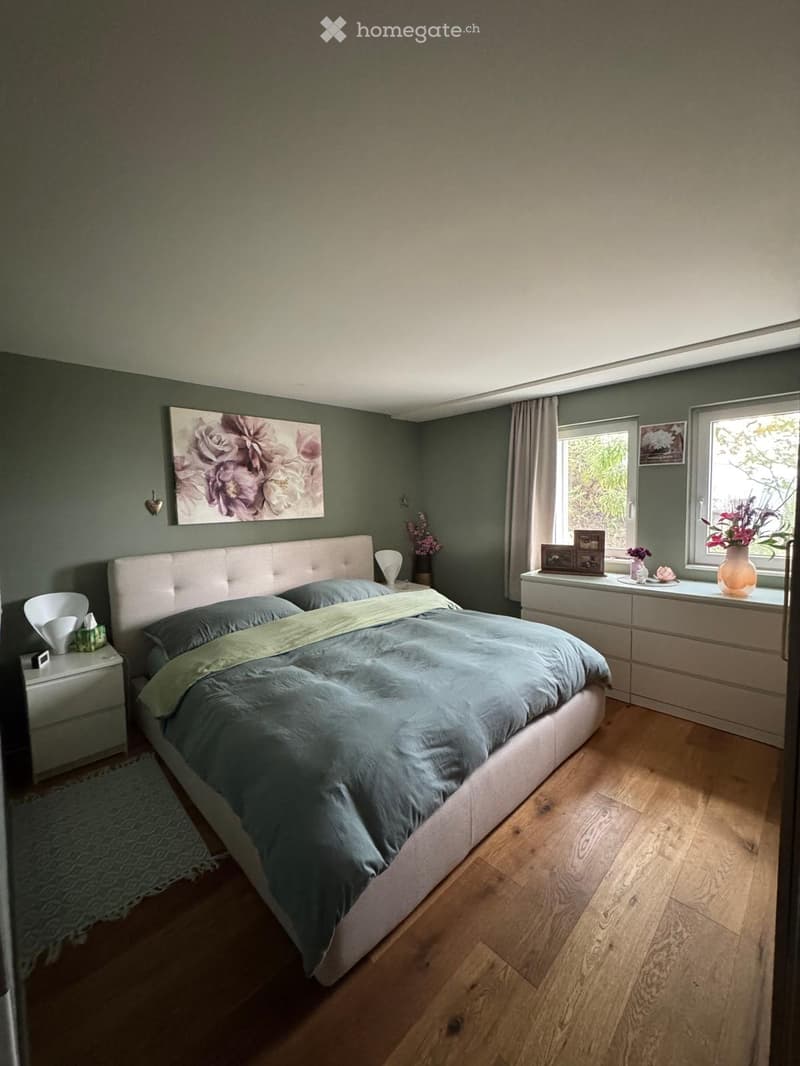 Modern bedroom with a large bed, nightstands, a window with a view, and decorative items on the windowsill.