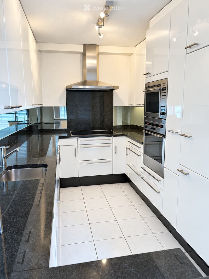 Modern kitchen with white cabinets, stainless steel appliances, granite countertops, and a tiled floor.
