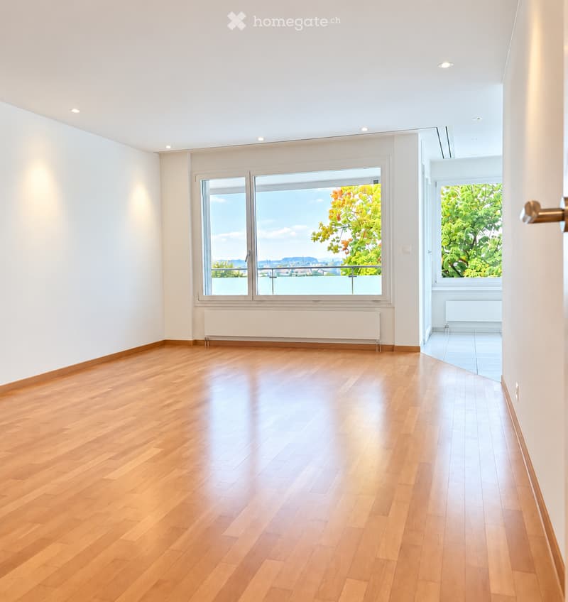 Empty room with wooden flooring, white walls, large windows, and a radiator. No furniture or equipment present.