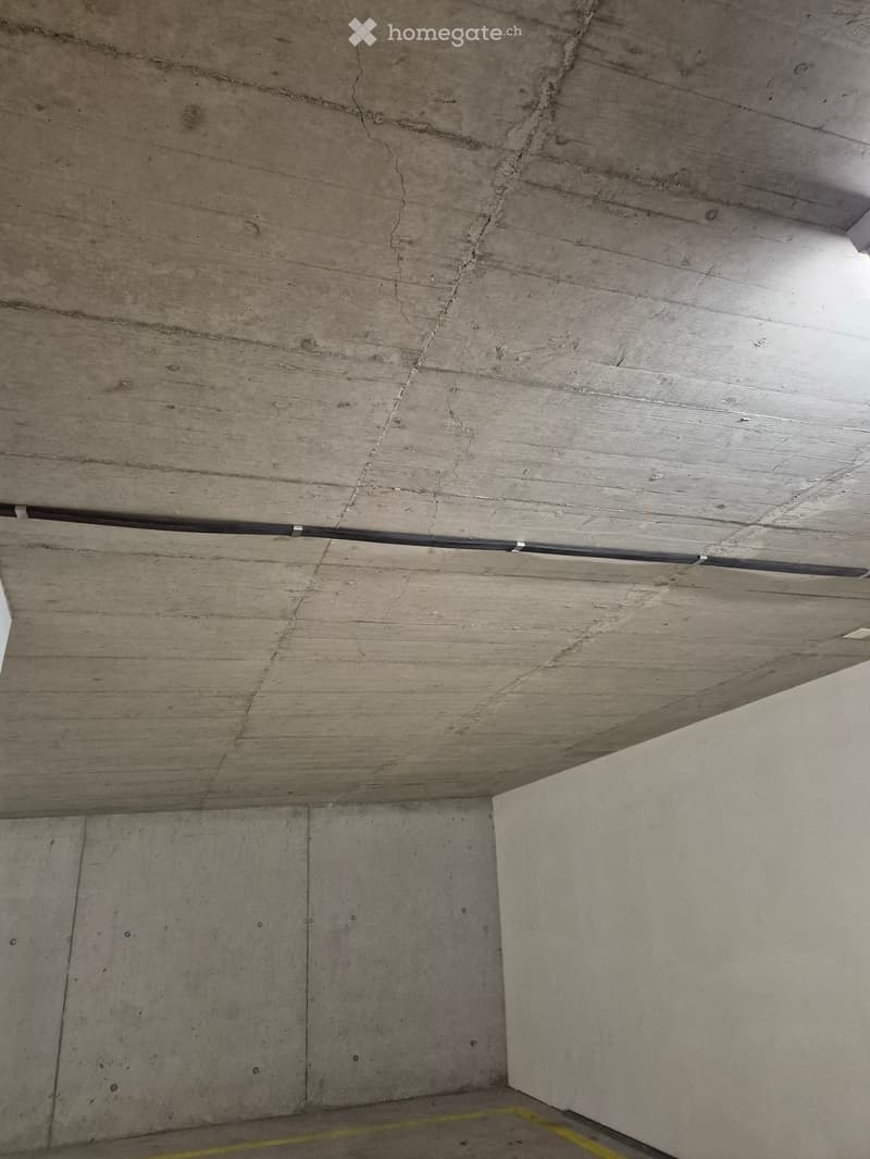 Concrete ceiling and walls with visible cracks and a yellow line marking the floor.