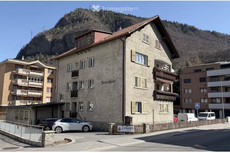 Multi-story residential building with a textured facade, multiple windows, balconies, and a name sign reading "Bieschborn".