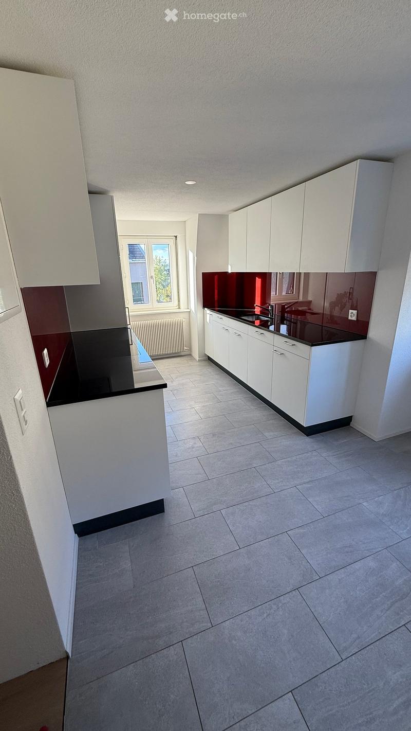 Modern kitchen with white cabinets, dark countertops, and a window overlooking a view.
