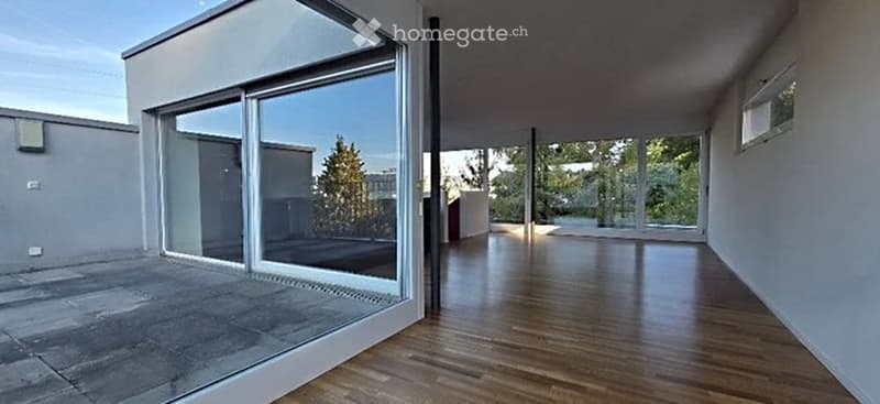 Open, unfurnished space with large glass sliding doors leading to a patio, wooden flooring, and white walls.