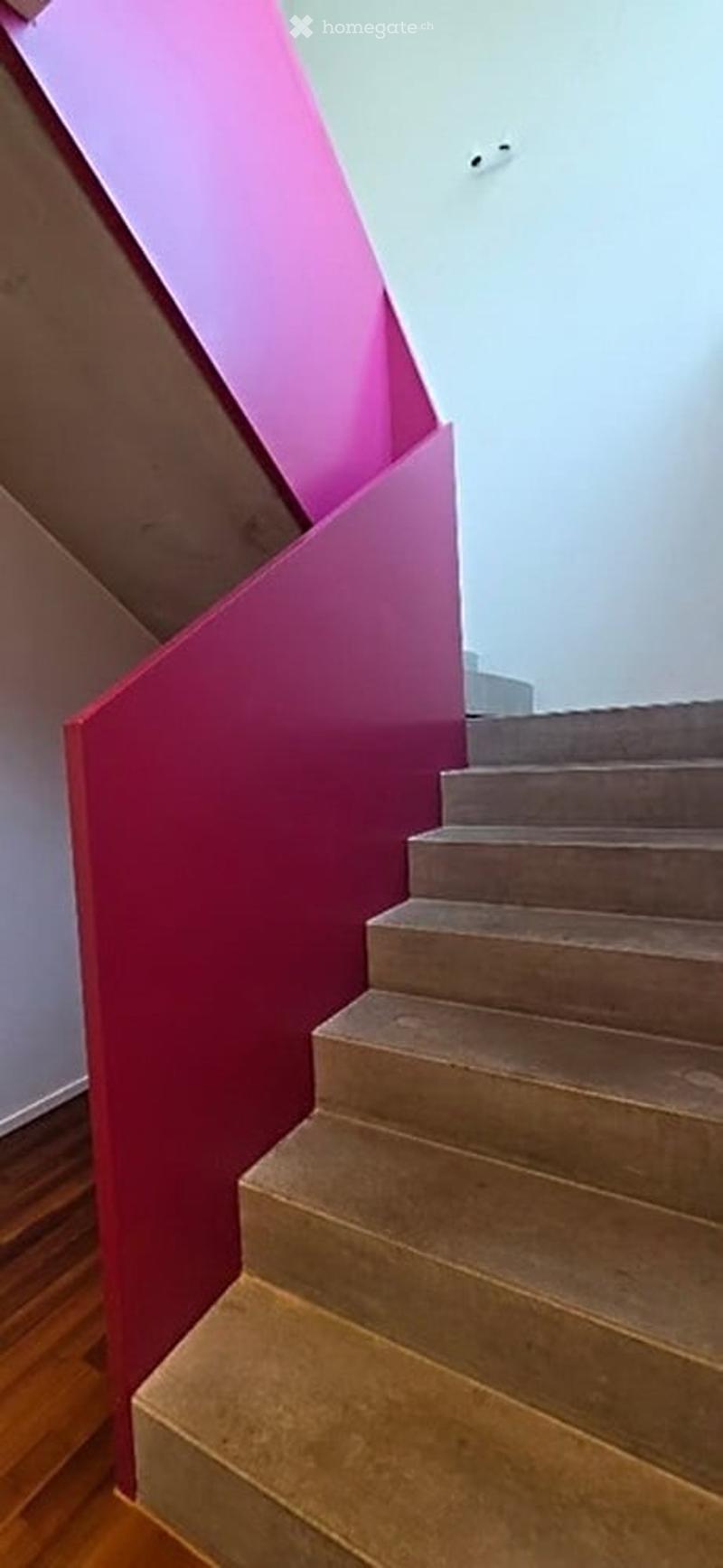 Staircase with pink painted walls and beige steps, wooden handrail, modern design.