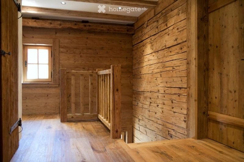 Completely empty room with wooden walls, floor, and a small window. No furniture or equipment.