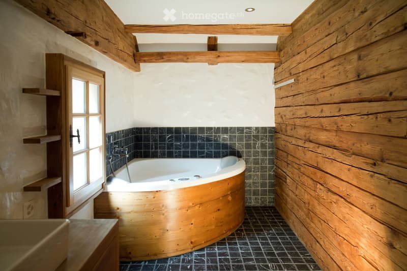 Bathroom with wooden walls, a wooden bathtub, black tiled floor, and a window with shelves.