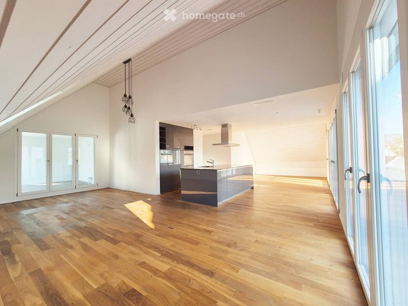Open-plan kitchen and living area with wooden flooring, large windows, and modern kitchen appliances.