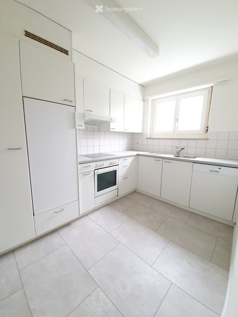 Modern kitchen with white cabinets, tiled backsplash, and stainless steel appliances including a refrigerator, oven, sink, and dishwasher.