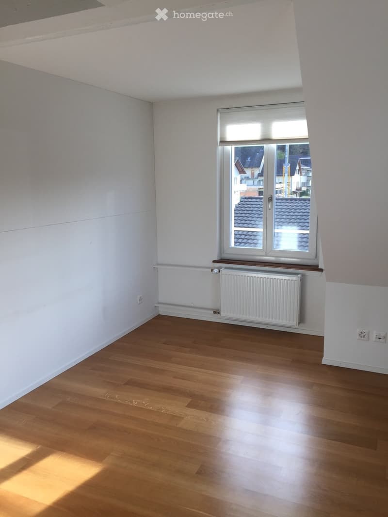 Empty room with wooden flooring, white walls, a window with blinds, and a radiator below the window.