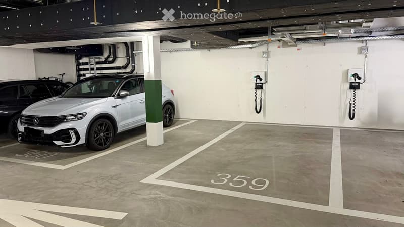 Underground parking area with marked parking spaces, two cars, charging stations, and structural pillars.