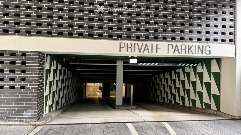 Entrance to a private parking area with a sign reading "PRIVATE PARKING" above the doorway. The interior shows a covered parking space with visible pillars and a green and white geometric design on the walls.