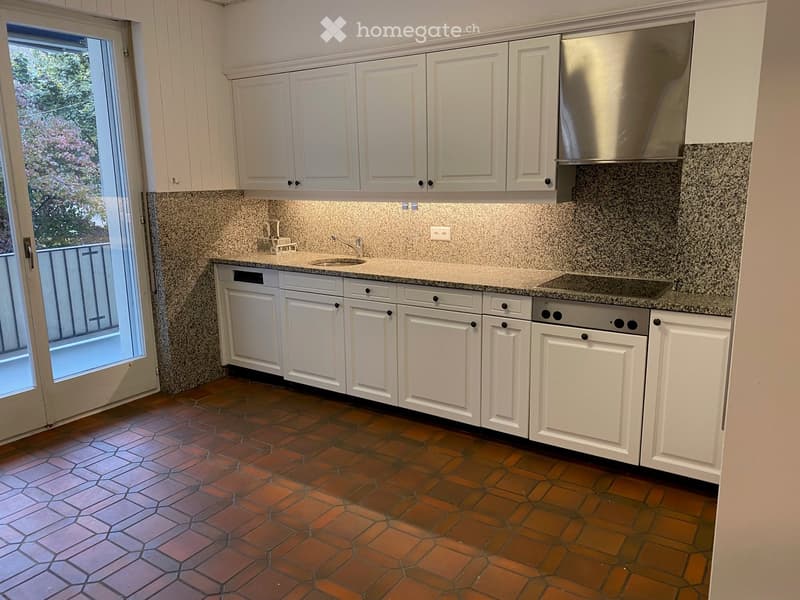 Modern kitchen with white cabinets, granite countertops, and a tiled floor. Features a sink, stove, and dishwasher.