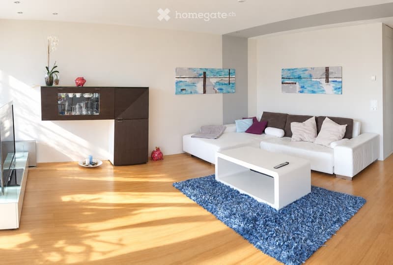 Modern living room with white sofa, coffee table, TV stand, cabinet, vase with flowers, and artwork on the walls.