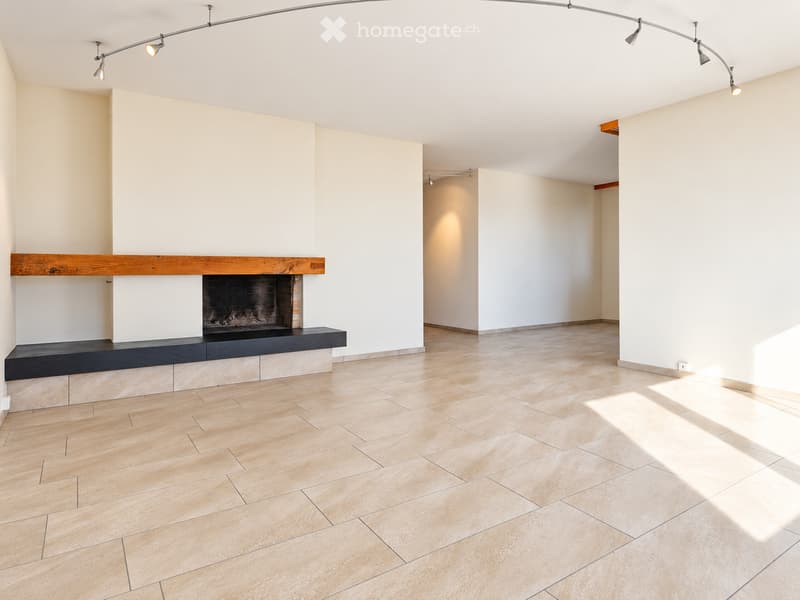 Empty room with tiled floor, white walls, and a fireplace with wooden mantel and black surround.