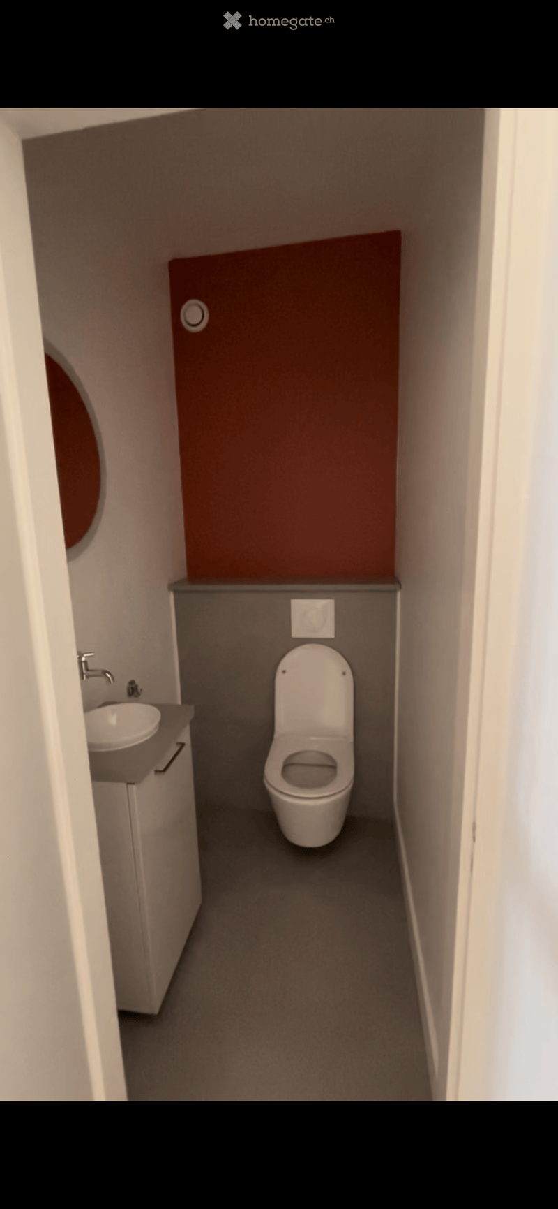 Modern compact bathroom with a toilet, sink, and faucet, featuring a dark grey wall and a brown accent wall.