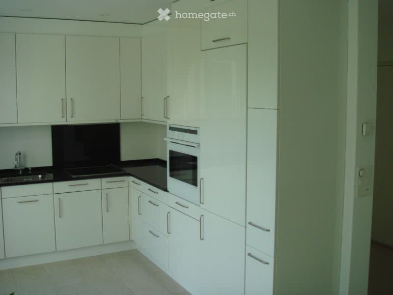 Modern kitchen with white cabinets, black countertops, and stainless steel sink and faucet.