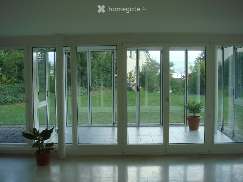 Bright, open room with large glass sliding doors leading to a patio, tiled floor, and two potted plants visible near the doors.