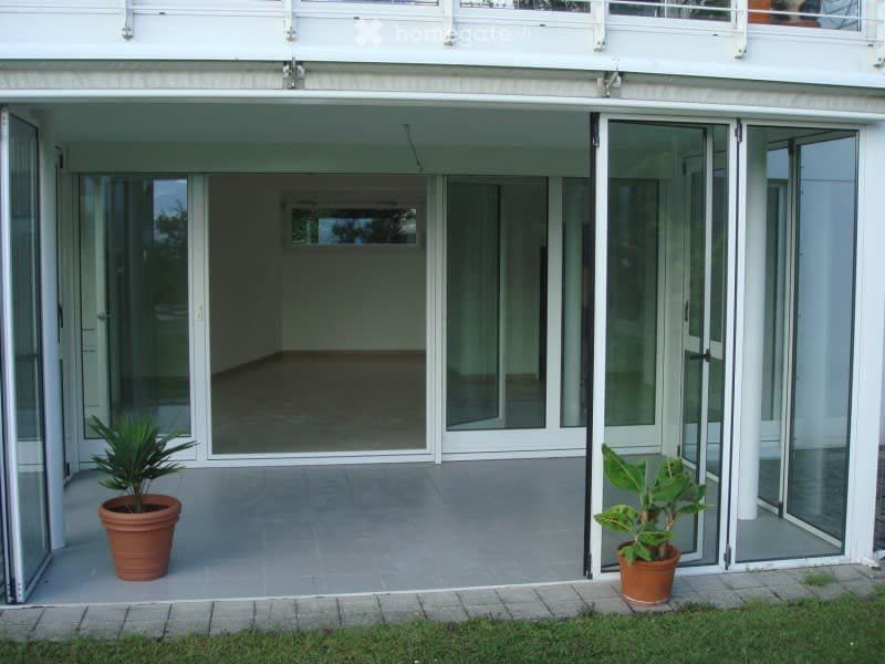 Balcony with large glass sliding doors, tiled floor, and two potted plants on either side.