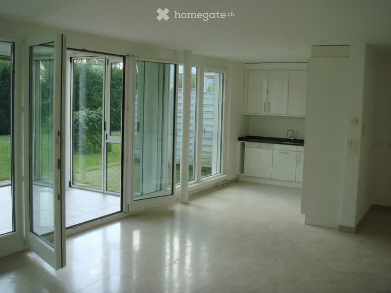 Bright, empty room with large sliding glass doors leading to a patio, white cabinetry, and a countertop.