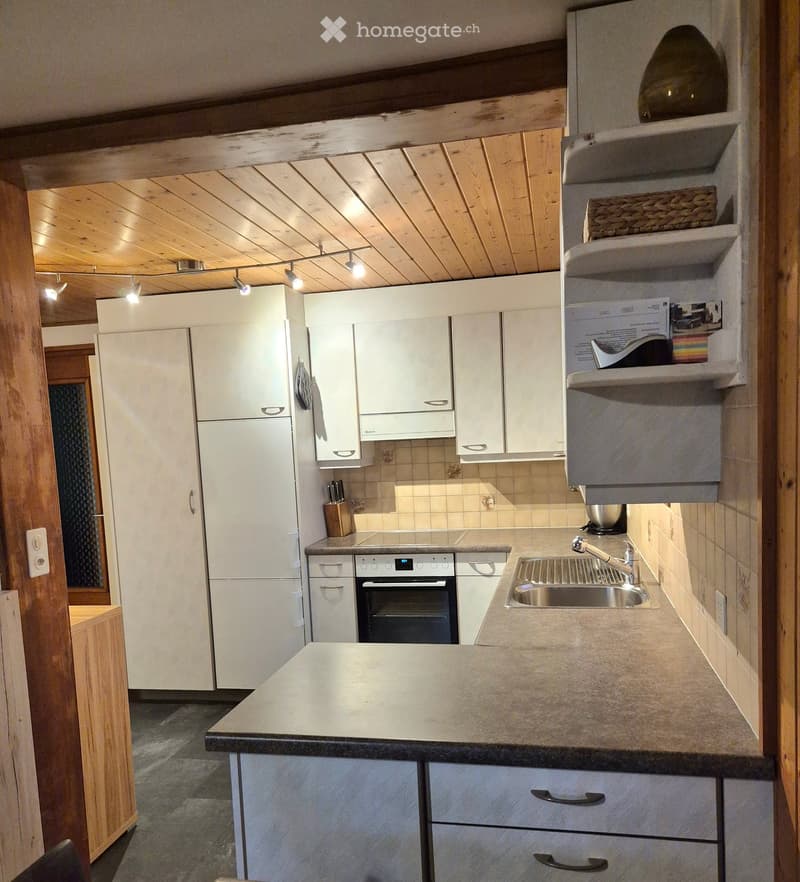 Modern kitchen with white cabinets, stainless steel appliances, and a central island. Features include a refrigerator, oven, sink, and countertop.