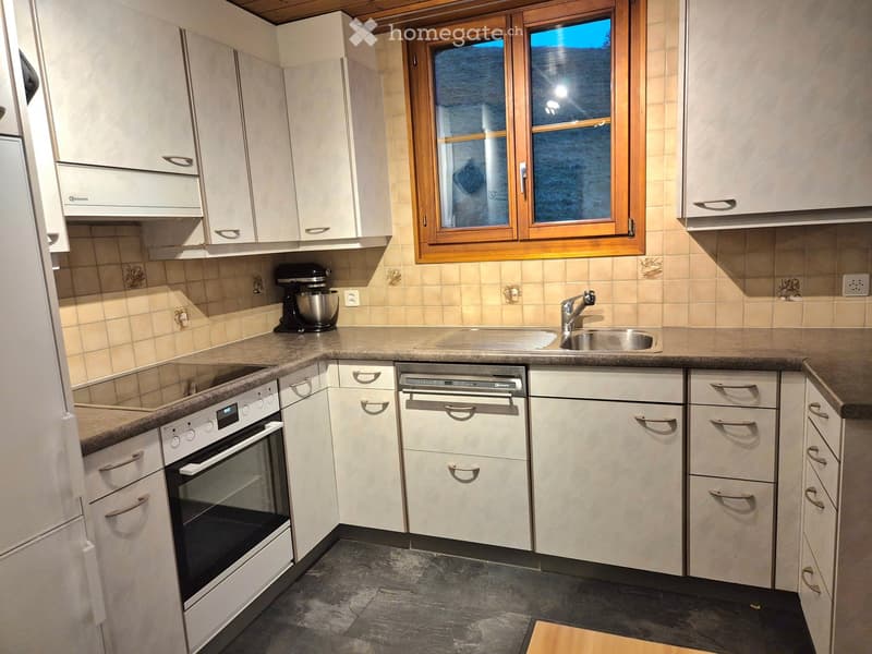 Modern kitchen with white cabinets, stainless steel appliances, granite countertops, and a window with wooden frame.