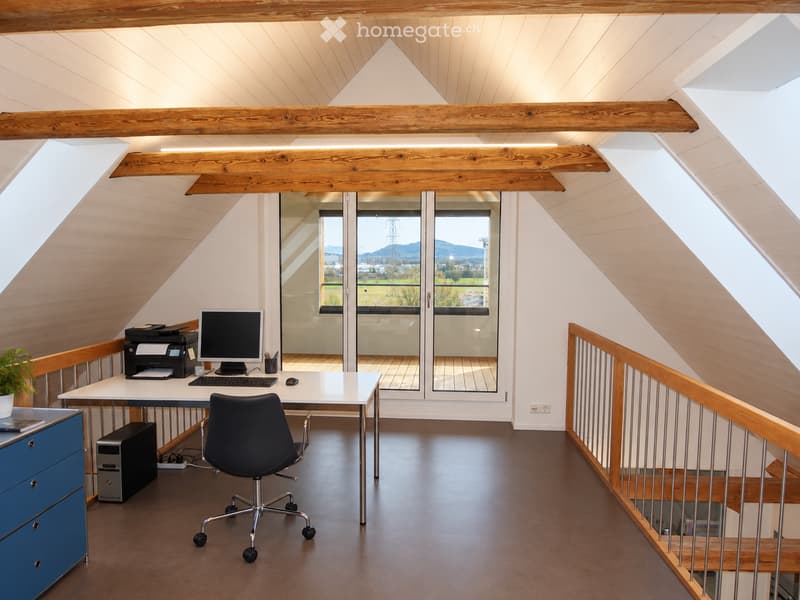 Modern attic office with slanted wooden ceiling, large windows, desk with computer, chair, printer, and cabinet.