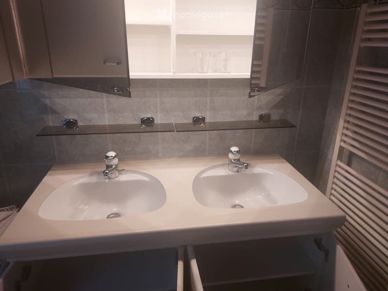 Modern bathroom with a double sink vanity, mirrored cabinet, and two glass shelves above the sink.