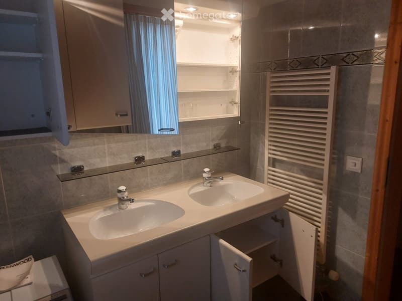 Modern bathroom with double sink, large mirror, built-in cabinets, and a radiator.