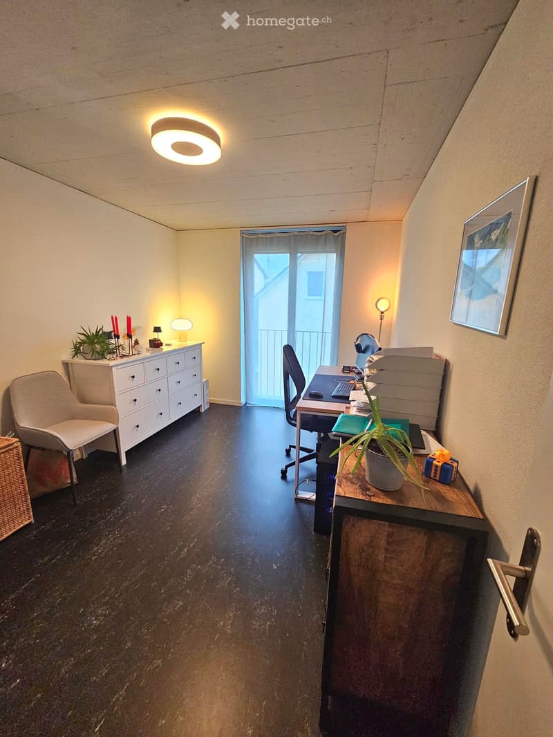 Office space with a desk, chair, cabinet, small table with plant, and a framed picture on the wall.