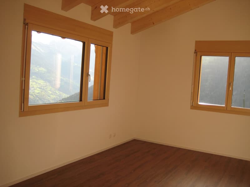 Empty room with wooden flooring, light-colored walls, and large windows offering a scenic mountain view.