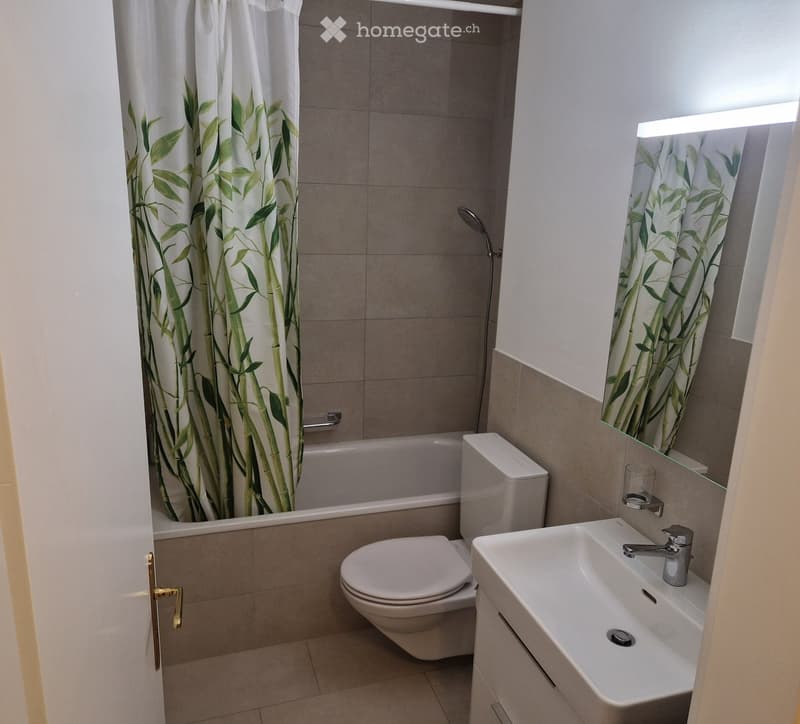 Modern bathroom with a bathtub, toilet, sink, and shower area with bamboo-patterned curtains.