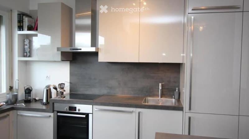 Modern kitchen with white cabinets, stainless steel appliances, and a dark grey backsplash.