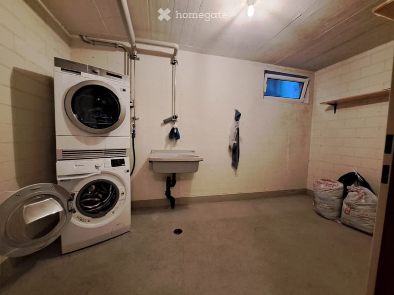 Utility room with a washing machine, dishwasher, and sink, featuring exposed brick walls and a small window.