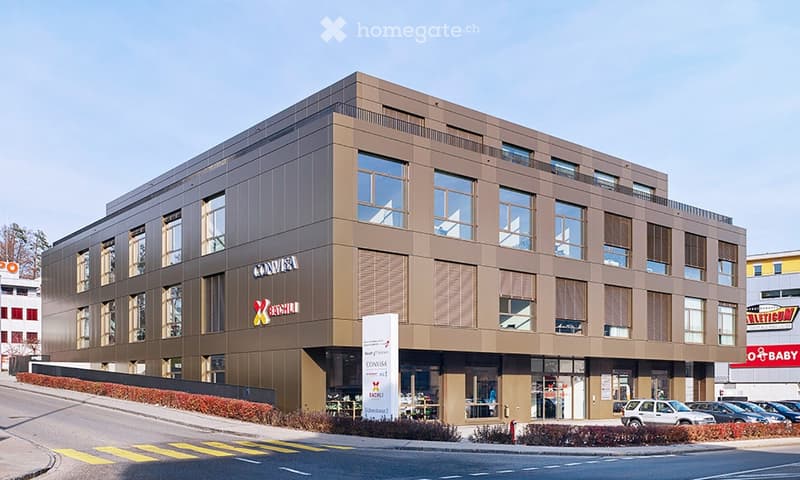Modern multi-story building with large windows and a sleek facade, featuring signage for 'CONVISA' and 'BACHELOR' on the exterior.