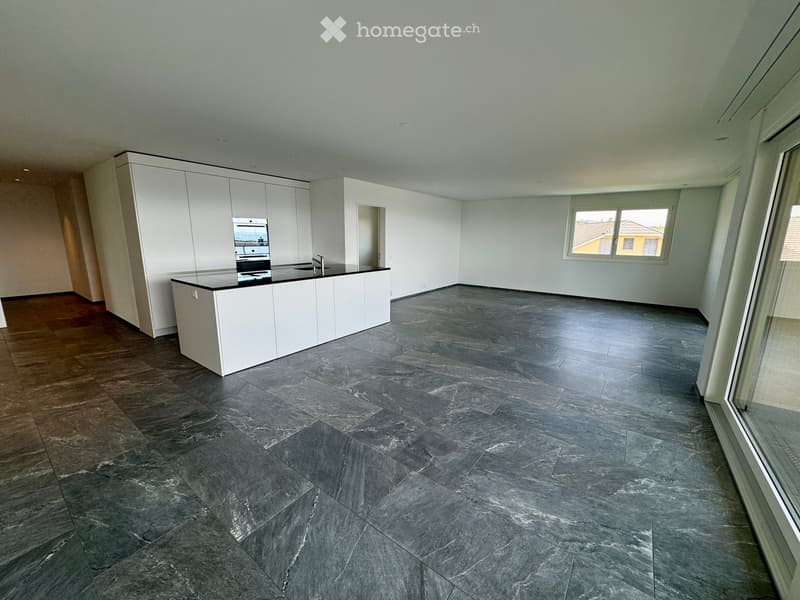 Empty kitchen with white cabinets, dark grey tiled floor, and large windows overlooking a neighboring house.