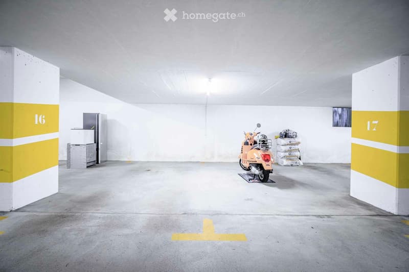 Underground parking area with a scooter, refrigerator, and storage boxes.