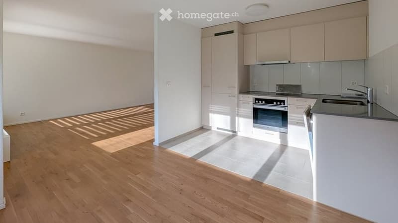 Modern kitchen with light-colored cabinets, a built-in oven, and a sink with a modern faucet. The floor is made of light wood, and the walls are white.