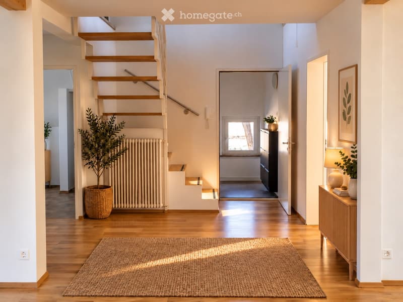 Bright hallway with wooden flooring, staircase leading upstairs, potted plants, and a small table with a lamp and books.