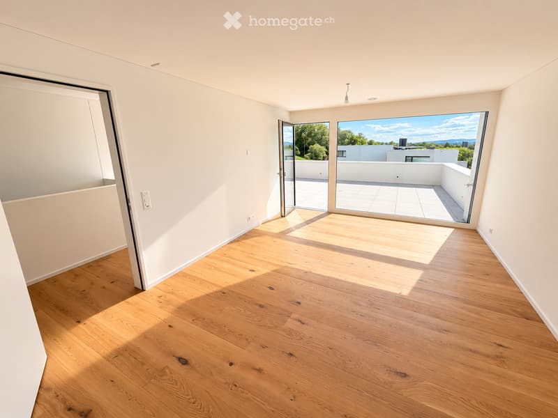 Empty room with light wooden flooring and white walls, featuring large glass doors leading to a balcony or terrace area.