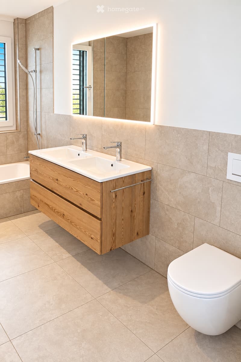 Modern bathroom with a double sink, wooden vanity, toilet, large mirror, and bathtub.