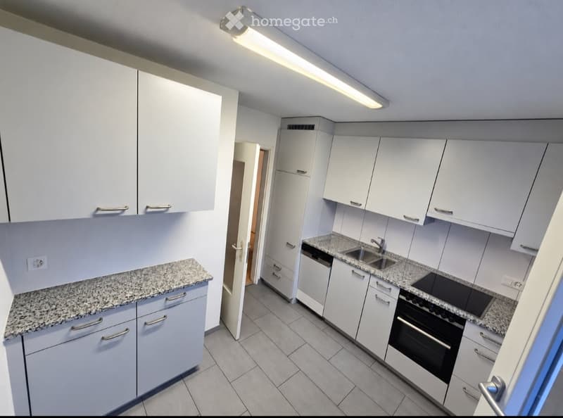 Modern kitchen with white cabinets, granite countertops, and stainless steel appliances including a sink, oven, and stove.