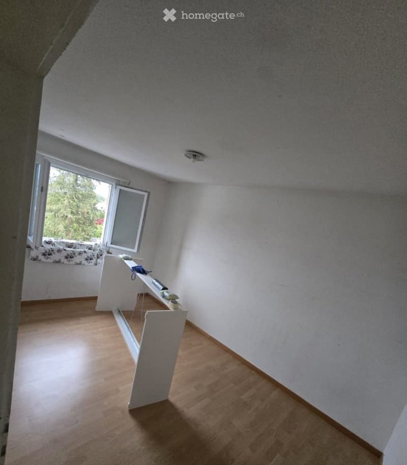Empty room with wooden flooring, white walls, and large windows with blinds. No furniture or equipment present.