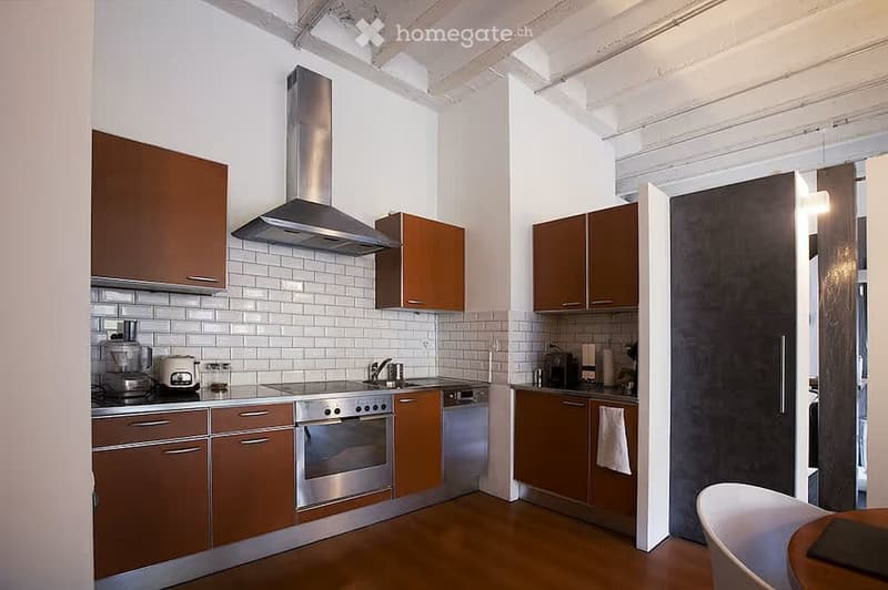 Modern kitchen with wooden cabinets, stainless steel appliances, white tiled backsplash, and a wooden floor.