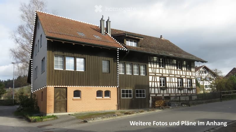 Two-story house with a combination of dark wooden siding and exposed timber framing, red-tiled roof, multiple windows, and a brick lower section.