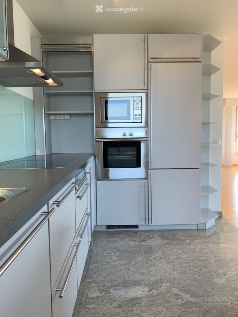 Modern kitchen with white cabinets, stainless steel appliances, and a dark countertop.