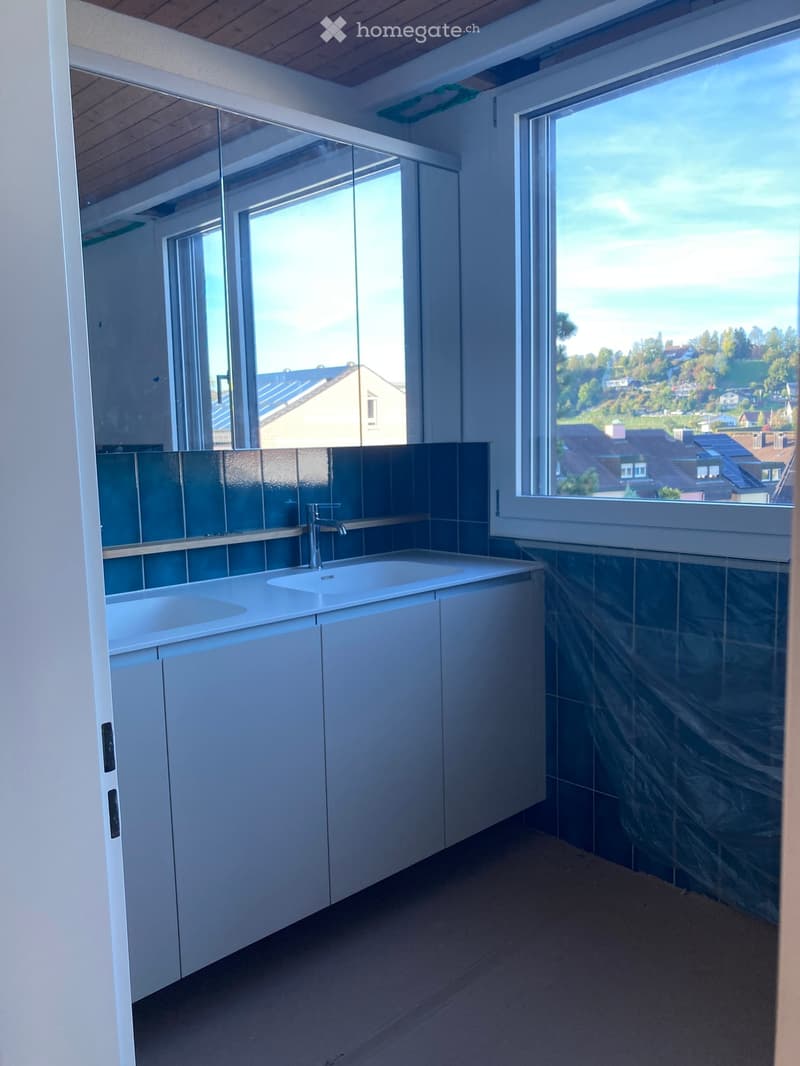 Modern bathroom with white cabinets, a double sink, and large windows offering a scenic view.
