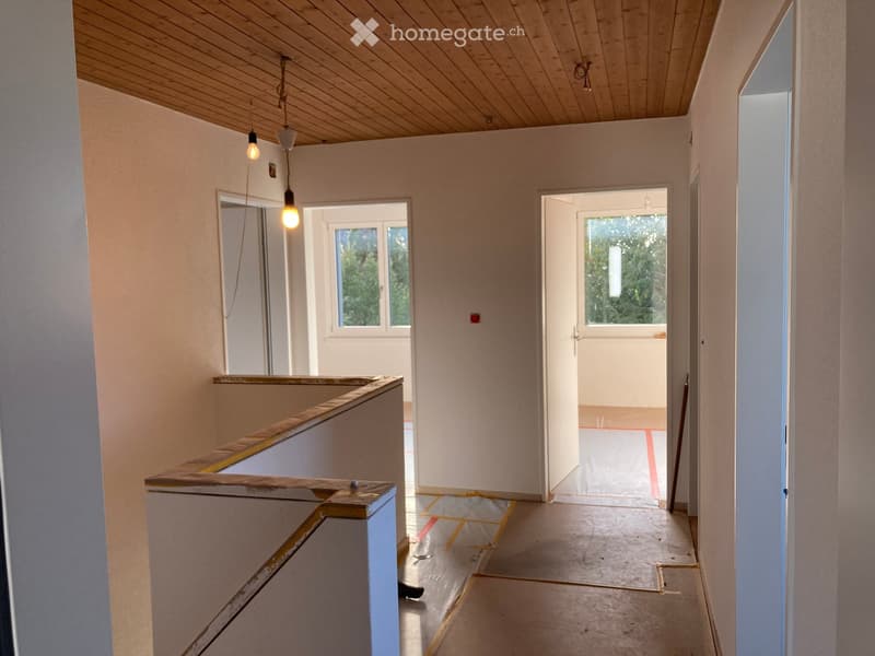 Empty hallway with wooden ceiling, pendant lights, and open doors leading to other rooms.