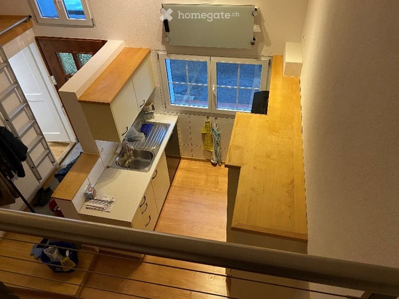 Compact kitchen with light wood cabinets, a sink, and a countertop. The space is small and functional, with a window providing natural light.